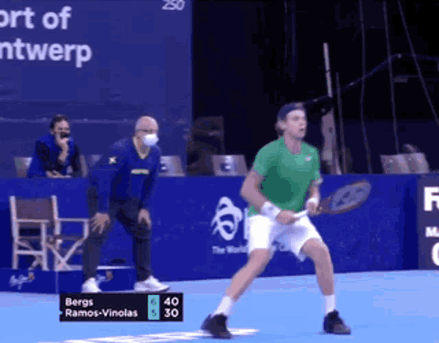 a man in a green shirt is playing tennis with a scoreboard that says berg ramos vinolas