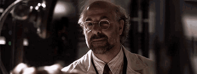 a man with glasses and a beard is wearing a lab coat