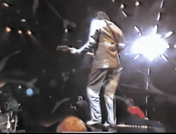 a man is playing a guitar on a stage in front of a crowd