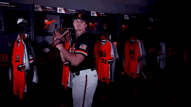 a baseball player in a locker room with the letter s on his cap