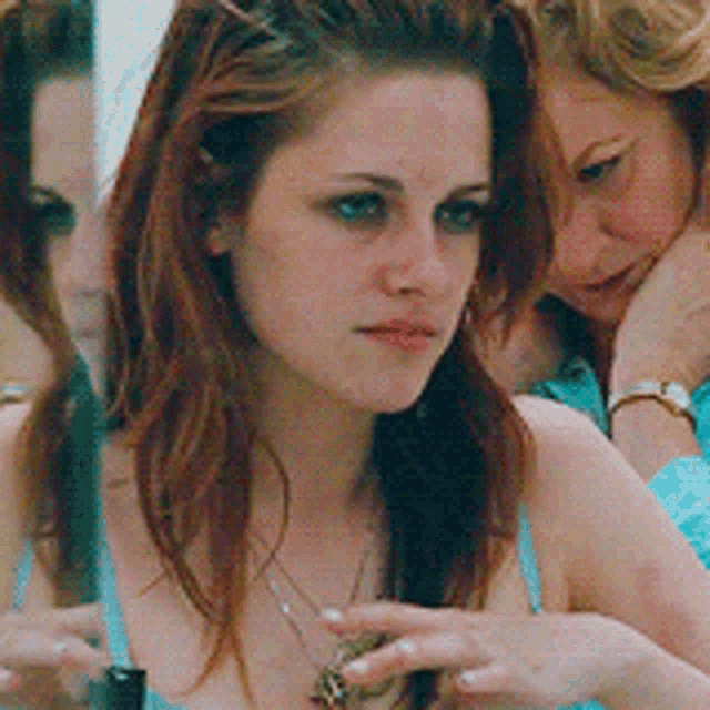 a woman in a blue tank top looks at herself in a mirror