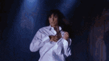 a naked woman is holding a white towel over her breasts in a dark room .
