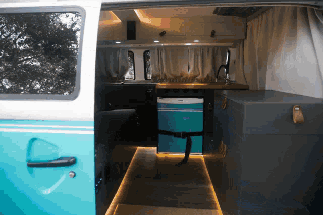 a blue and white van with the door open and a cooler in the back