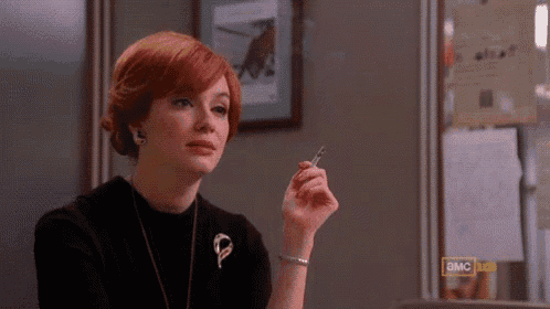 a woman with red hair is smoking a cigarette in front of a sign that says ' a.m.c ' on it
