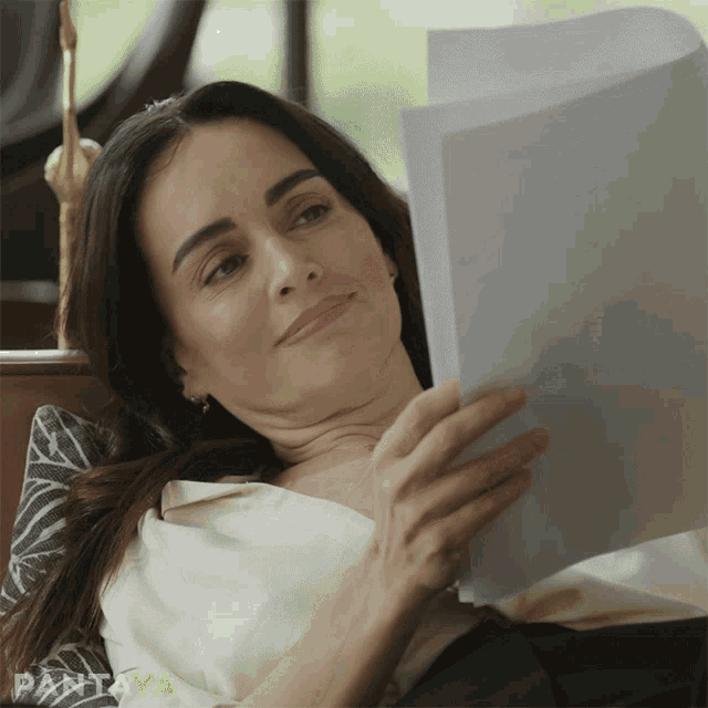 a woman laying on a couch reading a piece of paper with pantaya written on the bottom