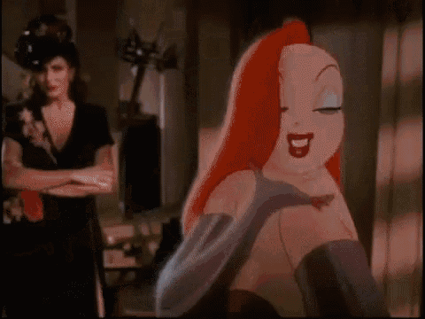 a cartoon character with red hair and purple gloves is standing in a room with a woman standing behind her .