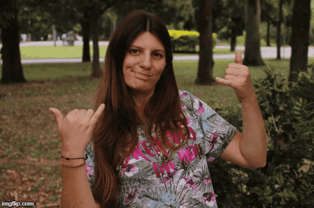 a woman in a floral shirt is giving a thumbs up sign