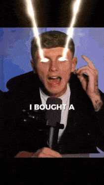 a man is talking into a microphone with light coming out of his eyes and the words i bought a