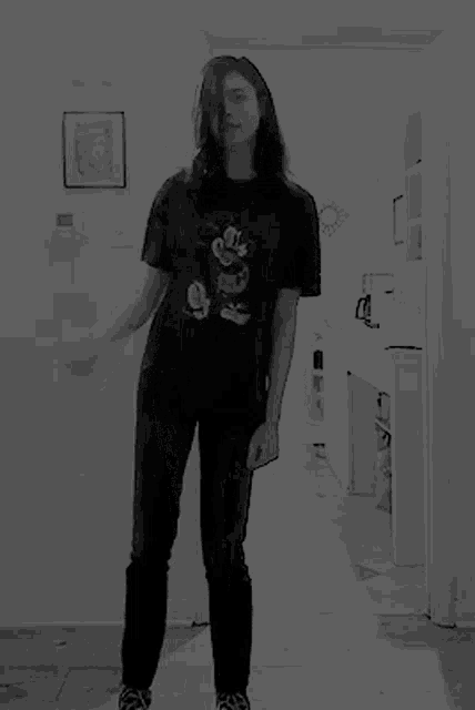 a woman is dancing in a hallway wearing a mickey mouse shirt .