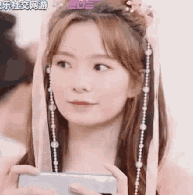 a woman is holding a cell phone in her hand and wearing a headband .