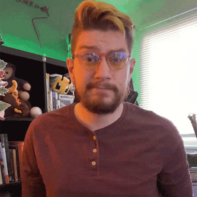 a man with a beard wearing glasses and a brown shirt