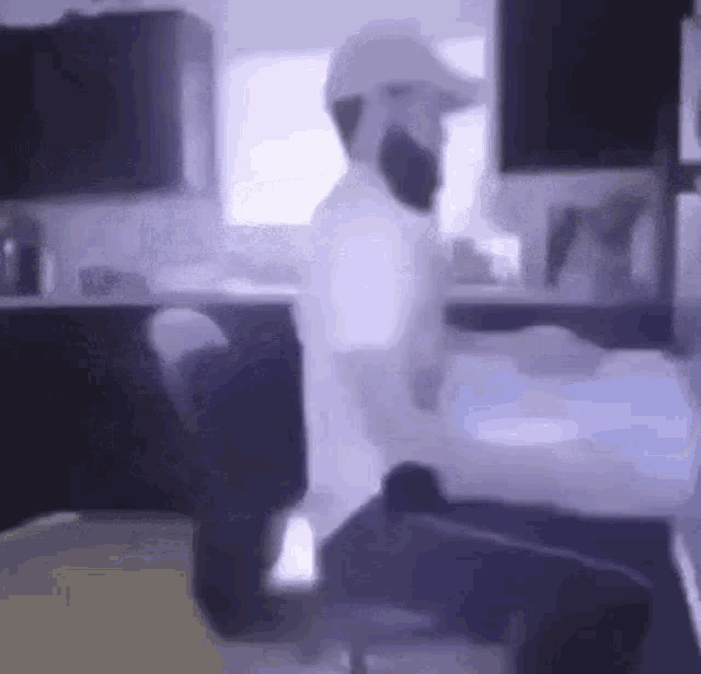 a man with a beard is sitting in a chair in front of a computer in a kitchen .