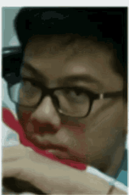 a man wearing glasses is brushing his teeth with a red toothbrush