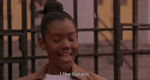 a woman is standing in front of a fence and smiling while saying `` i like italians . ''