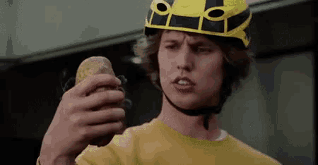 a man wearing a helmet is holding a potato .