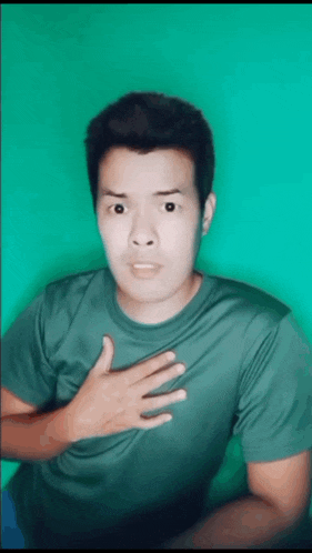 a man in a green shirt is making a surprised face