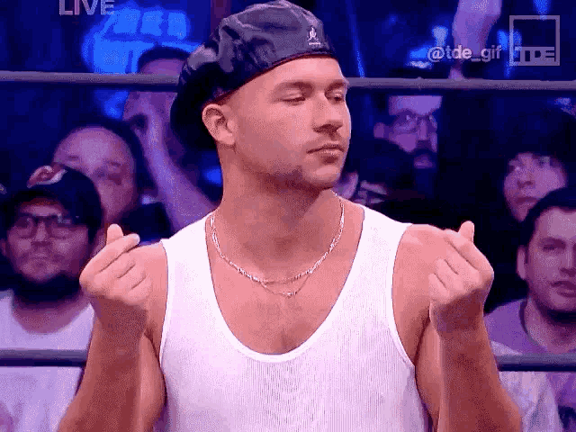a man wearing a beret and a tank top is making a gesture with his hands