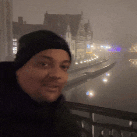 a man in a black hat stands in front of a foggy river