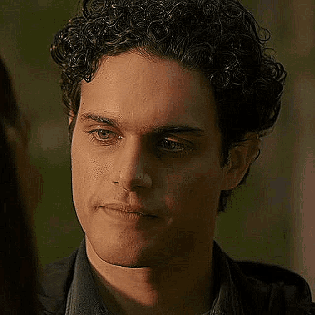 a close up of a man 's face with curly hair .