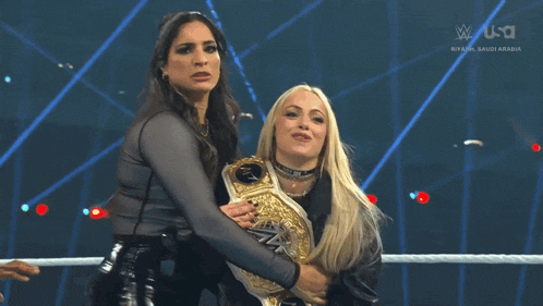 two women in a wrestling ring with the letters w on the bottom left