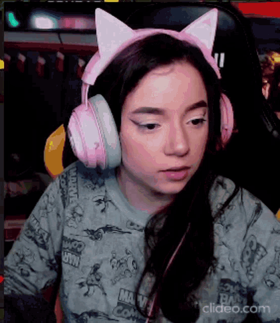 a girl wearing headphones and a cat ear headband is sitting in a chair .