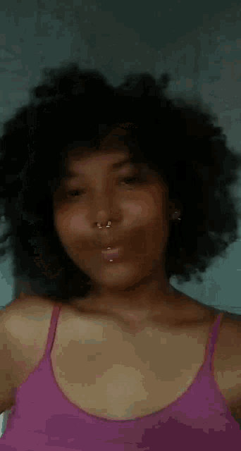 a woman in a purple tank top is making a funny face