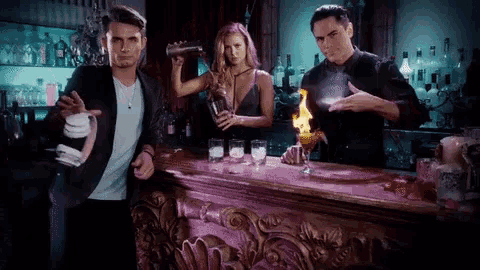 two men and a woman standing at a bar