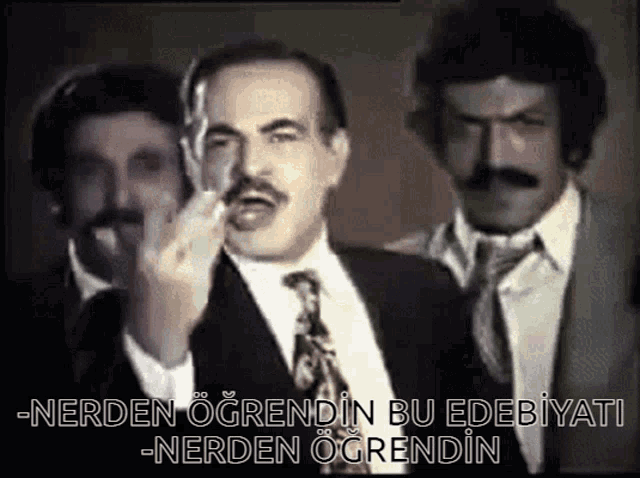 a man in a suit and tie is giving the middle finger to two other men