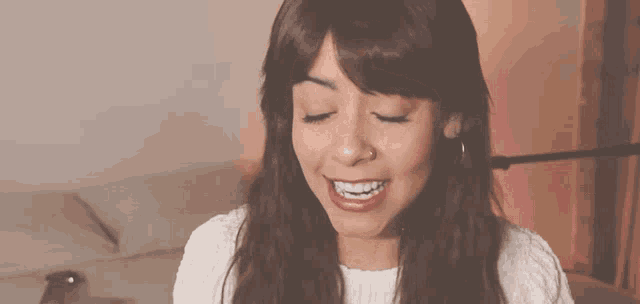 a woman with a nose ring is smiling and looking down