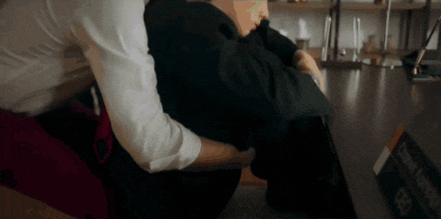 a man in a white shirt is hugging another man in a red apron