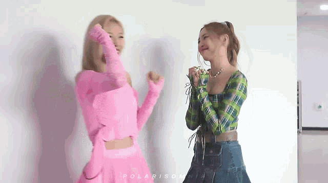 a woman in a pink top and a woman in a green plaid shirt are dancing together .