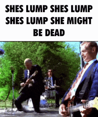a man in a suit and tie is playing a guitar in front of a band .