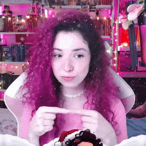a woman with purple hair wearing a santa hat is sitting in a pink chair