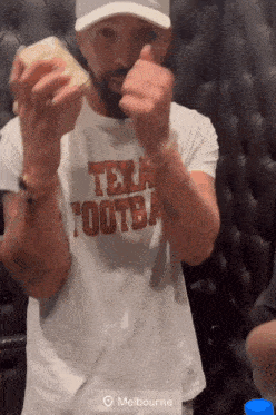 a man wearing a texas football shirt is giving a thumbs up sign