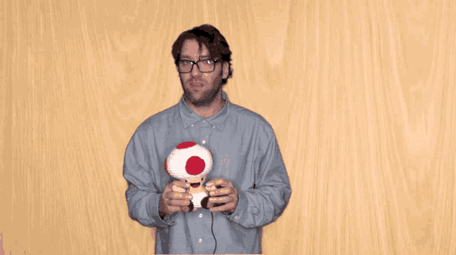 a man with glasses is holding a stuffed mushroom