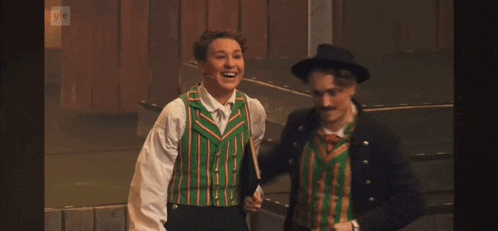a man and a woman are standing next to each other and the man is wearing a green vest