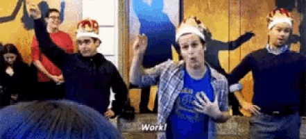 a group of men wearing crowns are dancing in a room and one man says work .