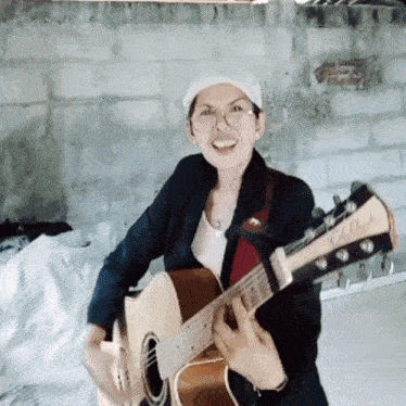 a woman wearing glasses and a hat is holding a guitar that says ' yamaha ' on the headstock