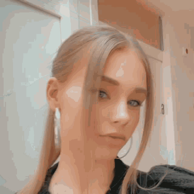 a woman wearing a black sweater and hoop earrings is taking a selfie