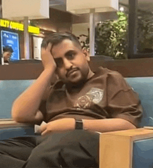 a man with a beard is sitting in a chair with his hand on his forehead .