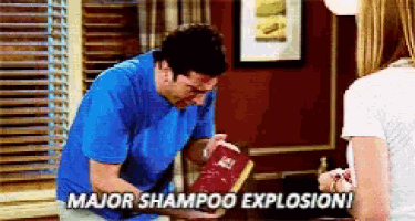 a man in a blue shirt is holding a bag of shampoo and says " major shampoo explosion "