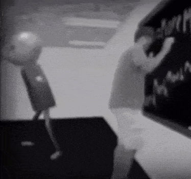 a man is writing on a blackboard in a room with a cartoon character .