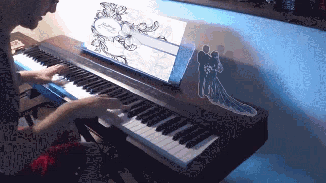 a man is playing a piano with a wedding invitation on top of it