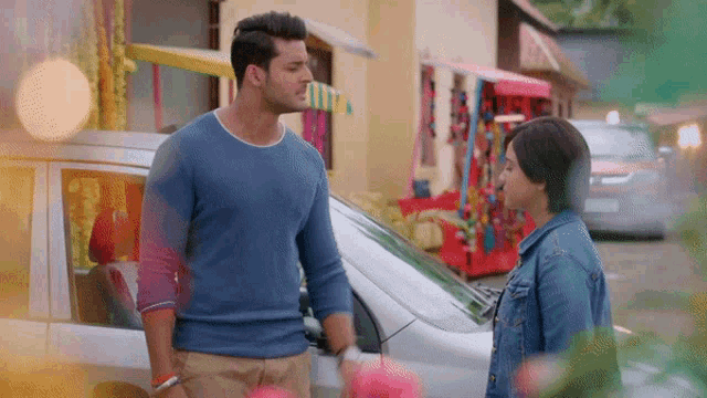 a man and a woman are standing in front of a white car