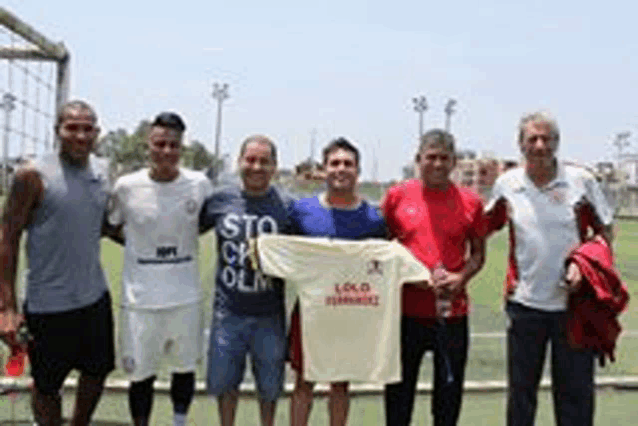 a group of men are standing next to each other on a soccer field holding a shirt .