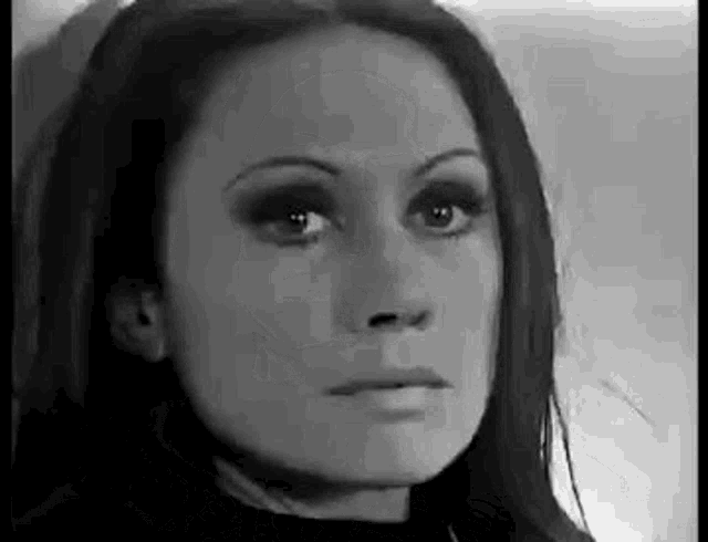 a black and white photo of a woman 's face with long hair .