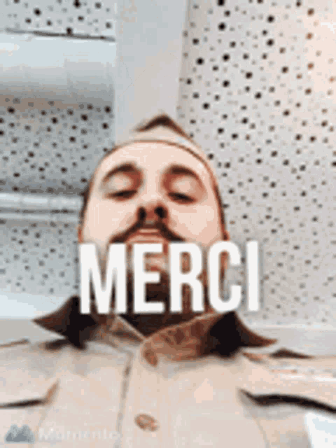 a man with a beard is wearing a hat and a shirt that says merci