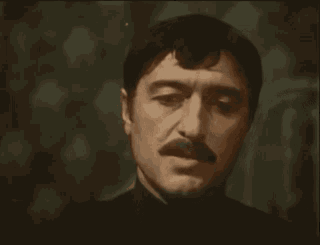 a man with a mustache is making a funny face in a close up of his face .