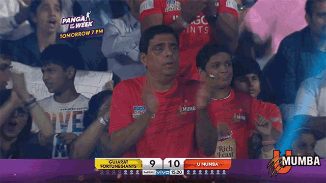 a man in a red shirt is watching a cricket game between gujarat fortune giants and u mumba