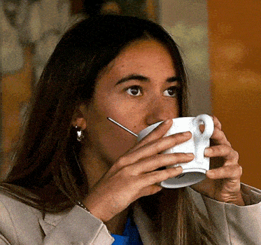 a woman is drinking a cup of coffee with a spoon .